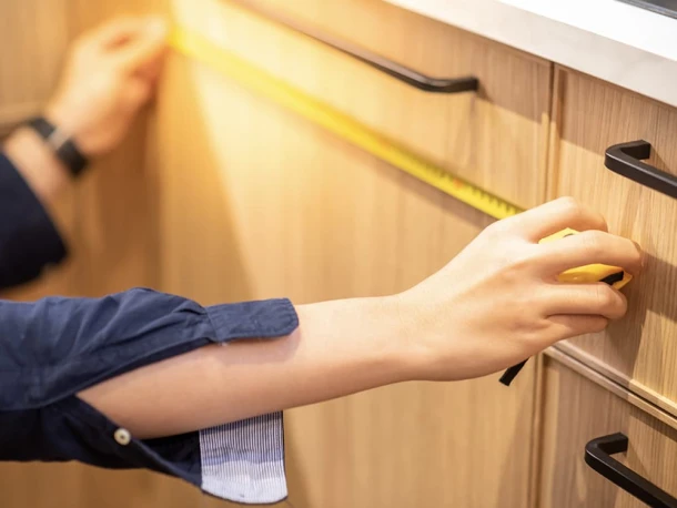 man measuring wooden kitchen door with measuring tape