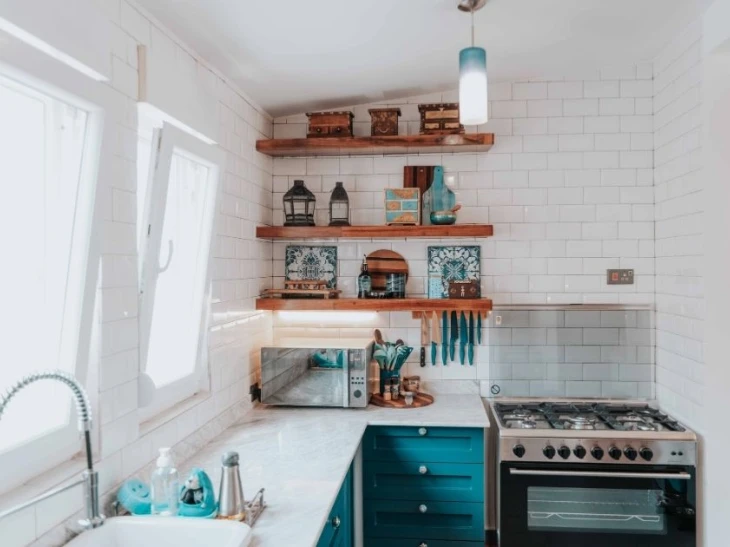 Corner of a kitchen with shelves, cutlery, oven, and a stove